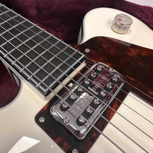 Close-up of electric guitar fretboard, strings, and chrome pickup with tortoiseshell pickguard and cream body.