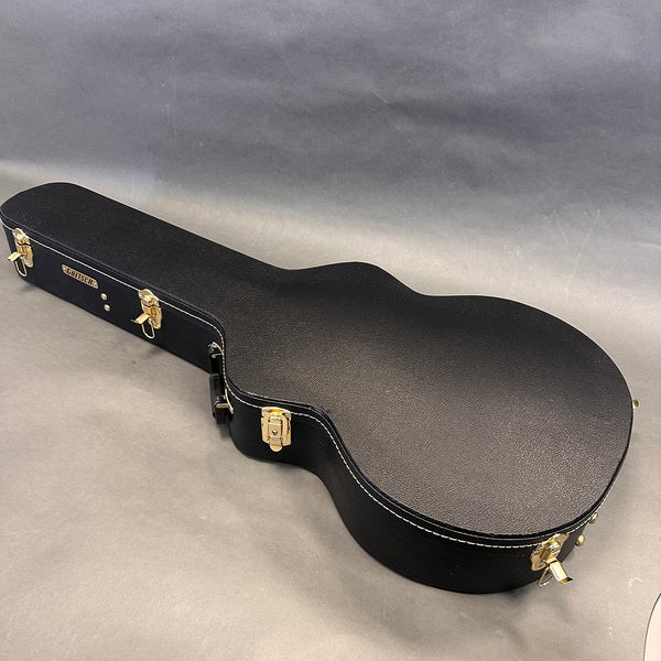 Black hard shell Gretsch guitar case with gold latches and white stitching on neutral gray background