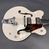 White Gretsch hollow body electric guitar with Bigsby vibrato tailpiece and double humbucker pickups on gray background