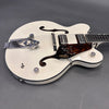 White Gretsch hollow body electric guitar with Bigsby vibrato tailpiece and dual humbucker pickups on gray background