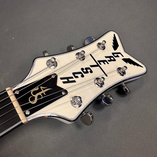 Close-up of white Gretsch guitar headstock with black logo and chrome tuning pegs on gray background