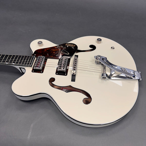 White hollow body electric guitar with Bigsby tremolo, dual humbucker pickups, and tortoiseshell pickguard on gray background