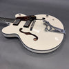 White hollow body electric guitar with Bigsby vibrato tailpiece and dual humbucker pickups on gray background