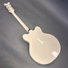Back view of white semi-hollow electric guitar with glossy finish and chrome tuning pegs on grey background