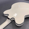 Glossy white semi-hollow electric guitar back with black binding and strap button on gray background