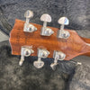 Close-up of mahogany guitar headstock with Grover tuning pegs and visible serial number and "Made in USA" stamp, resting on a plush gray guitar case lining