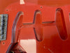 Close-up of red electric guitar body routing cavities for pickups and bridge hardware without pickups installed