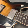 Close-up of semi-hollow body electric guitar with sunburst finish, chrome humbucker pickups, rosewood fretboard, and binding details on body and neck