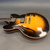 Semi-hollow body electric guitar with sunburst finish, dual humbucker pickups, black pickguard, and four control knobs on gray background
