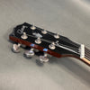 Close-up of Gibson acoustic guitar headstock with tuning pegs and strings on gray background