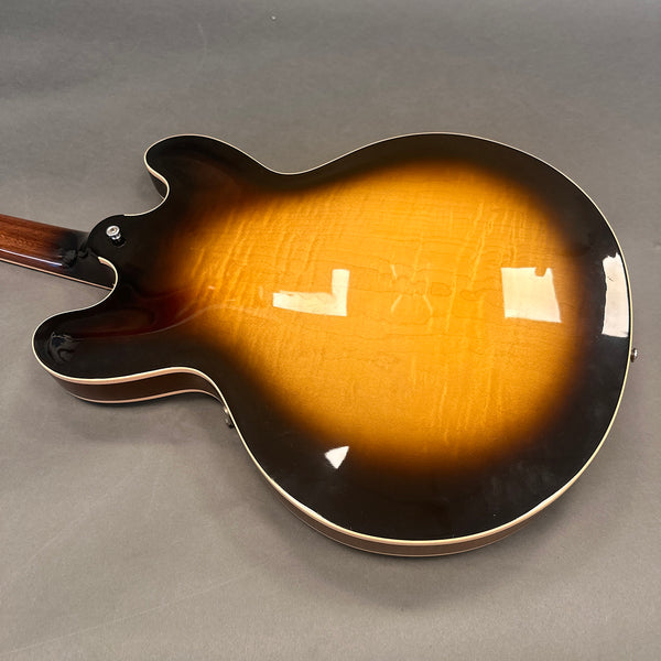 Back of sunburst semi-hollow electric guitar with glossy finish and cream binding against gray background