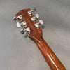 Back of guitar headstock and neck showing six chrome tuning pegs with serial number and "Made in USA" stamp on mahogany wood guitar neck against gray background