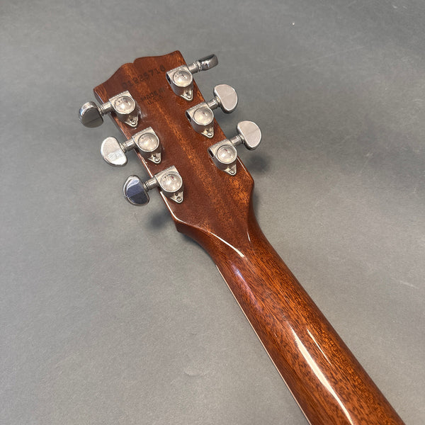 Back of guitar headstock and neck showing six chrome tuning pegs with serial number and "Made in USA" stamp on mahogany wood guitar neck against gray background