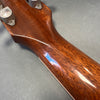 Close-up of glossy polished wood neck and tuning pegs on acoustic guitar against gray background