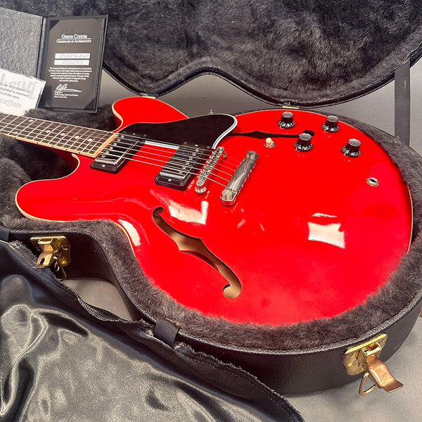 Red Gibson semi-hollow electric guitar with black pickguard and dual humbucker pickups in open black hard case with certificate of authenticity