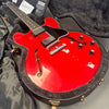 Red semi-hollow electric guitar with black pickguard and dual humbucker pickups in open black fuzzy lined hard case with certificate of authenticity from Coffee House Guitars