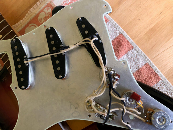 Vintage guitar pickguard with three single-coil pickups and wiring exposed, ideal for Stratocaster guitar repair or upgrade at Coffee House Guitars.