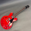 Red semi-hollow body electric guitar with dual humbucker pickups, black pickguard, and rosewood fretboard on gray background