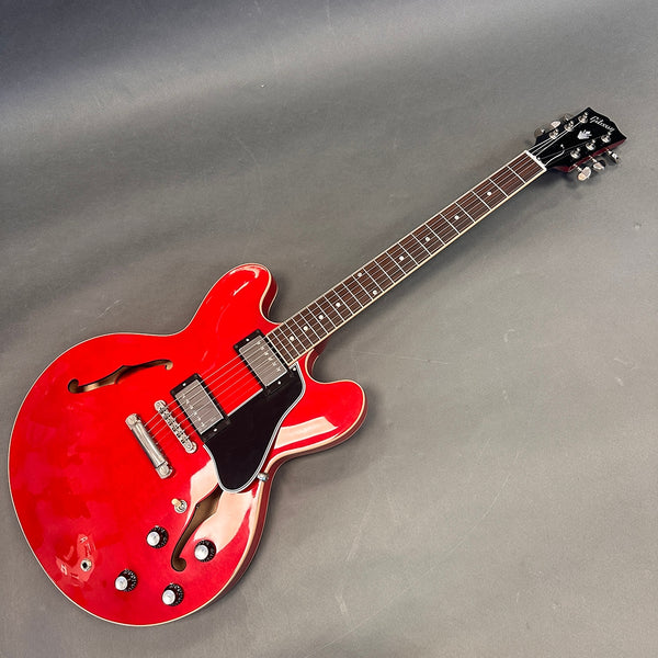 Red semi-hollow body electric guitar with dual humbucker pickups, black pickguard, and rosewood fretboard on gray background