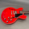 Red semi-hollow electric guitar with black pickguard and dual humbucker pickups on gray background