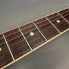 Close-up of rosewood guitar fretboard with metal frets and white dot inlays on a light wood edge background