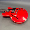 Red semi-hollow electric guitar with black pickguard and chrome hardware on gray background