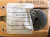 Close-up of worn vintage guitar neck plate with partial handwritten and stamped labeling, featuring aged Phillips screws and signature marking on light wood background.