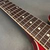 Close-up of red electric guitar fretboard with metal frets and dot inlays on rosewood neck