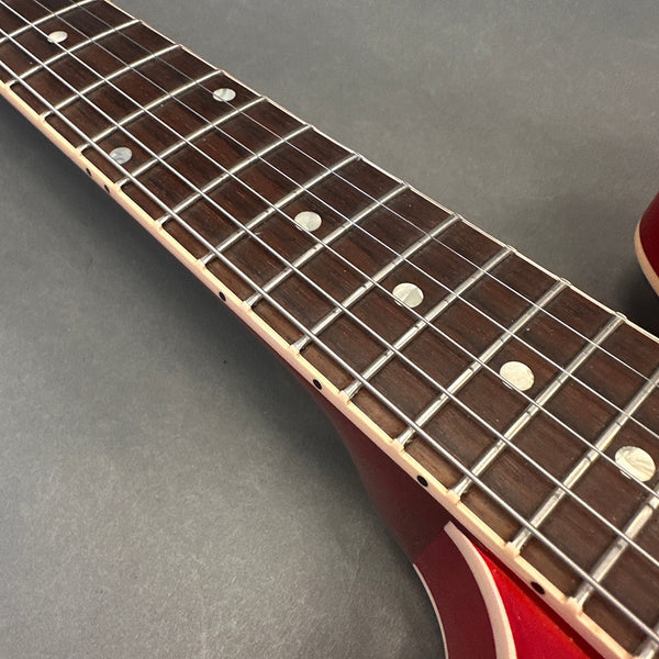 Close-up of red electric guitar fretboard with metal frets and dot inlays on rosewood neck