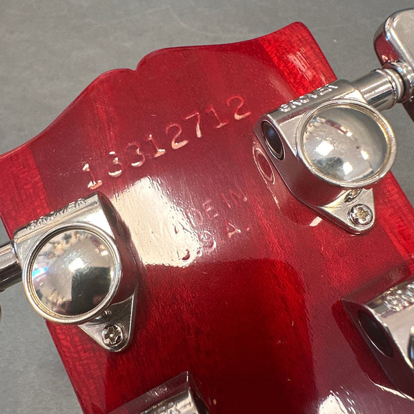 Close-up of red guitar headstock back showing serial number 13312712, made in U.S.A., with chrome Grover tuning pegs