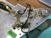 Close-up of electric guitar control plate showing internal wiring, potentiometers, capacitors, and switch assembly for vintage-style guitar electronics.
