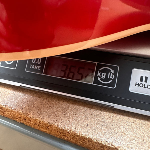 Close-up of a red guitar body on a digital scale showing a weight of 3.65 pounds at Coffee House Guitars.