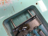 Close-up of inside cavity of vintage electric guitar showing metal spring claw attached with two screws, with visible soldering and turquoise finish.