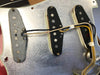 Close-up image of three single-coil guitar pickups mounted on a metal pickguard plate with visible wiring and solder points, showing detailed construction and internal components for electric guitars.