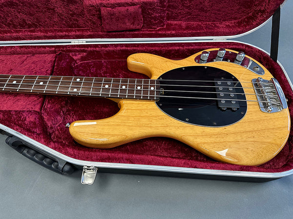 Natural finish electric bass guitar with black pickguard and chrome hardware in red velvet-lined hard case