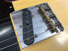 Close-up of Fender Telecaster vintage single-coil bridge pickup and metal bridge plate with adjustable brass saddles on natural wood guitar body.