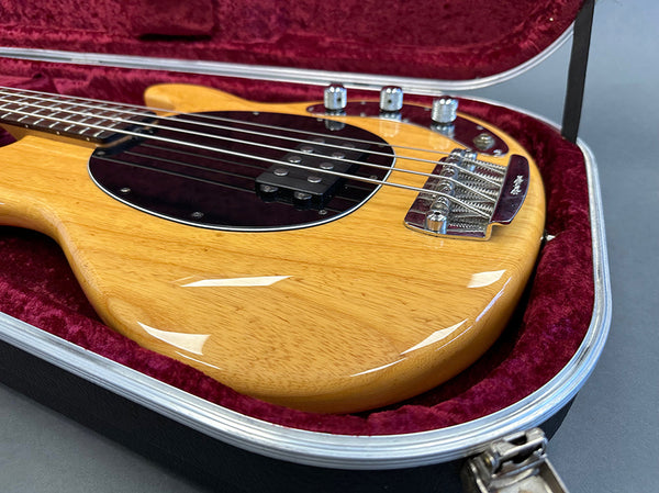 Natural wood finish electric bass guitar body with black pickguard and chrome bridge in red velvet lined guitar case