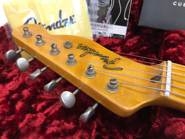 Fender guitar headstock with six tuning pegs on red plush guitar case interior, Fender manual and cloth in background