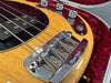 Close-up of Music Man bass guitar bridge and pickups on natural wood finish body in red velvet-lined guitar case