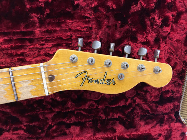 Close-up of Fender guitar headstock with six tuning pegs and maple fretboard on plush red case interior