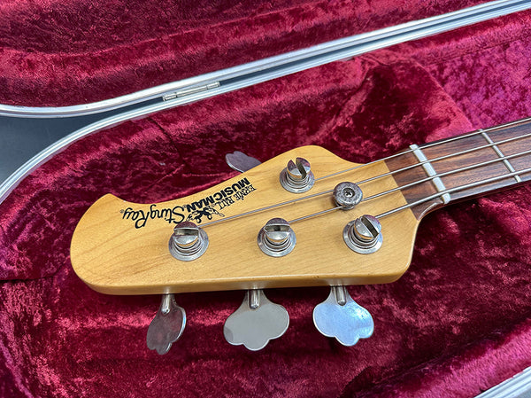 Fender MusicMan StingRay bass guitar headstock with tuning pegs in red velvet guitar case
