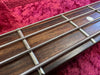 Close-up of bass guitar fretboard with metal frets and wound strings on red fabric background