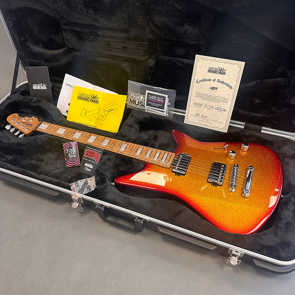 Ernie Ball Music Man electric guitar with sparkling orange finish and maple neck in black hard case with certificate of authenticity and branded accessories