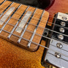 Close-up of electric guitar fretboard with rectangular inlays and metal frets, featuring a metallic orange glitter finish and chrome pickups and strings.