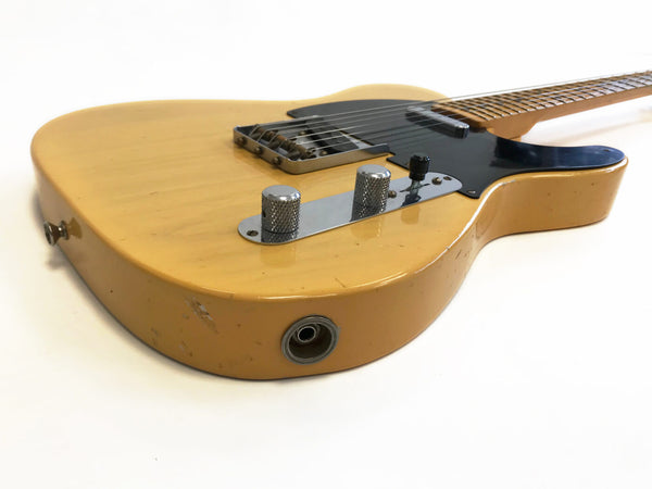 Vintage-style electric guitar with worn yellow finish, black pickguard, chrome control knobs, and steel bridge on white background