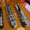Close-up of chrome bridge and tailpiece on electric guitar with gold sparkle finish and metal strings