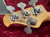 Close-up of guitar tuning pegs on wooden headstock with "Made in San Luis Obispo California, USA" stamp, resting on red velvet background