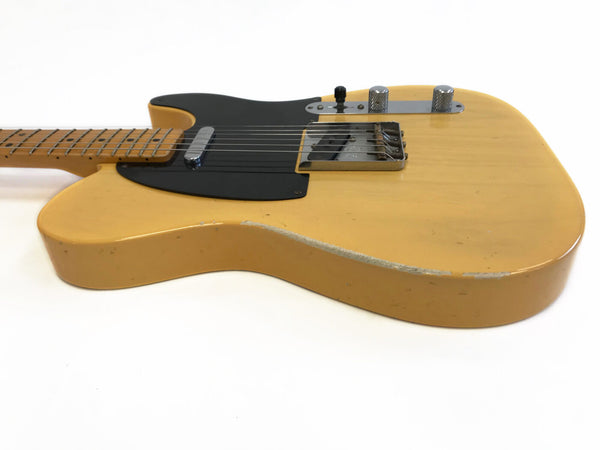 Vintage yellow electric guitar with black pickguard and maple neck showing wear and chipped paint on body