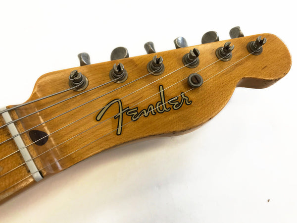 Close-up of vintage Fender guitar maple headstock with six tuning pegs and strings on white background