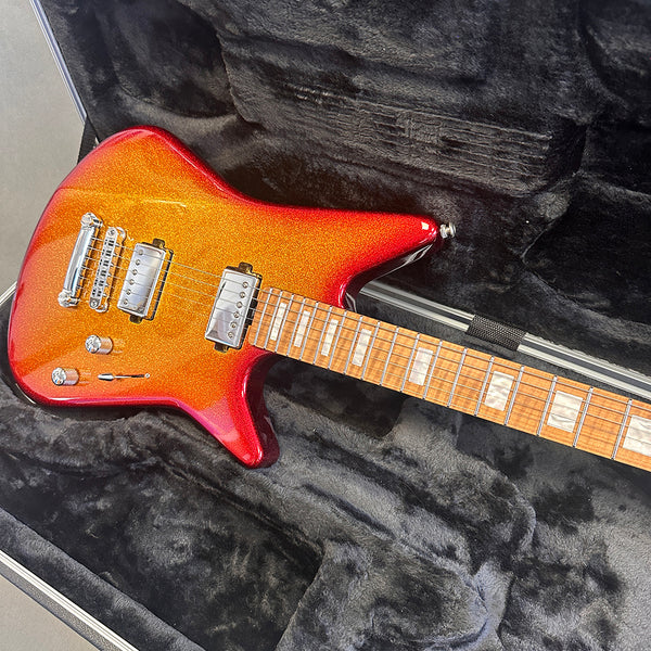Electric guitar with orange and red sparkle finish, two humbucker pickups, and maple neck in black plush guitar case